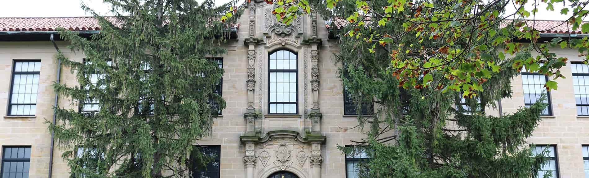 Architecture building from the outside with trees in front of windows.