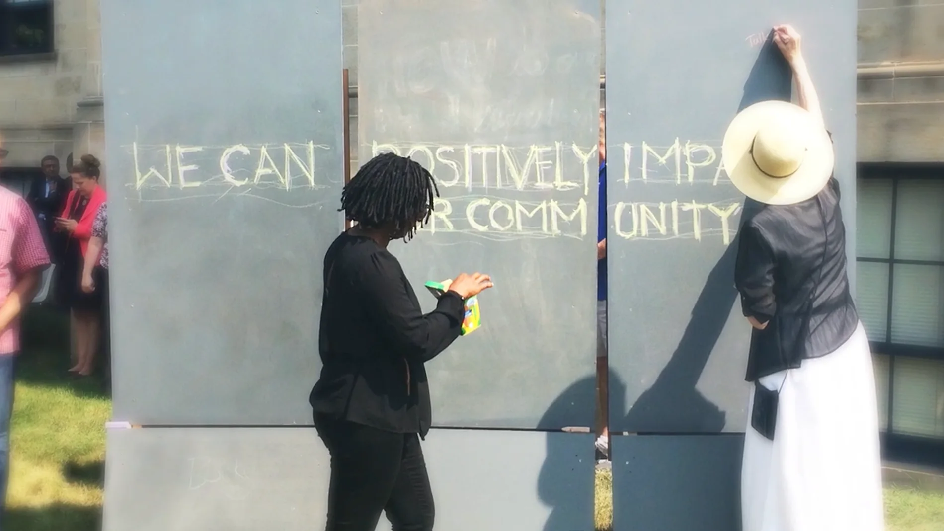 people looking at a community sign that says we can.